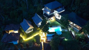 Vista aérea de una zona residencial con varias casas, una piscina y senderos bien iluminados.
