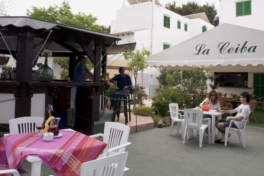 Ein Außenbereich mit Tischen und Stühlen, eine Bar und ein Gebäude mit der Aufschrift 'La Ceiba'.