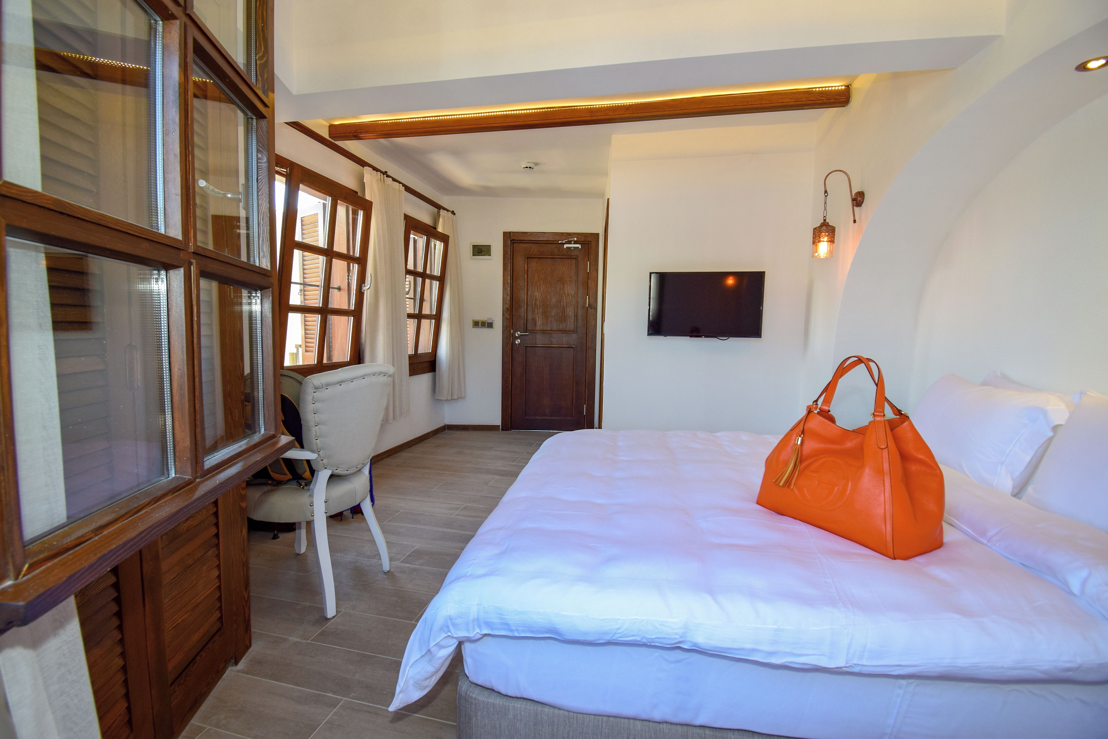 A hotel room with a bed, a chair, a television, and a large window with curtains.