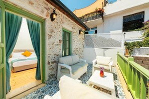 A balcony with wicker furniture, a bed with a green door, and a white fence. - Mets Boutique Hotel (Marmaris)