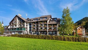A hotel with multiple floors, balconies with plants, and a clear view of the surrounding landscape. - Hotel Cerkno (Cerkno)