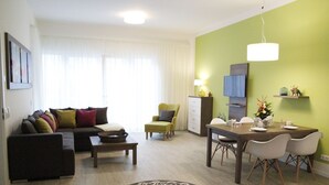Ein modernes Wohnzimmer mit Sofa, Couchtisch und Essbereich mit Stühlen und einem Tisch für zwei Personen.