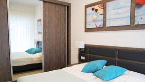 Ein Hotelzimmer mit einem Bett, einem Nachttisch, einem Spiegel und einer Wand mit gerahmten Kunstwerken.