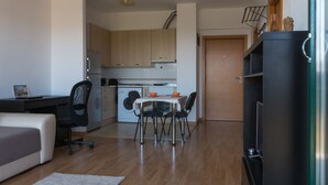 A compact kitchen with modern appliances, a dining area with a table and chairs, and a living area with a sofa and a TV stand. - AdrianApartments (Cluj-Napoca)