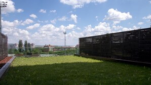 A grassy outdoor area with a metal fence and a sports field in the background. - AdrianApartments (Cluj-Napoca)