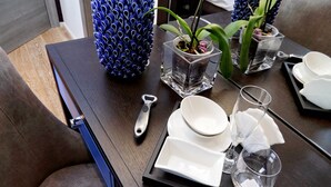 A dining table with a tray containing white dishes, glasses, and a bottle opener. There are two potted plants with blue and green leaves. - Luxurious three-room apartment with balcony, at the corner of Via Veneto (Roma)