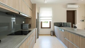 A modern kitchen with wooden cabinets, stainless steel appliances, and a large window providing natural light. - Eudora Luxury Stone Villa (Apokoronas)