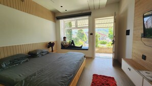 A modern bedroom with a large bed, a window seat, and a TV mounted on the wall. - Viewtoria Resort (Dhanaulti)