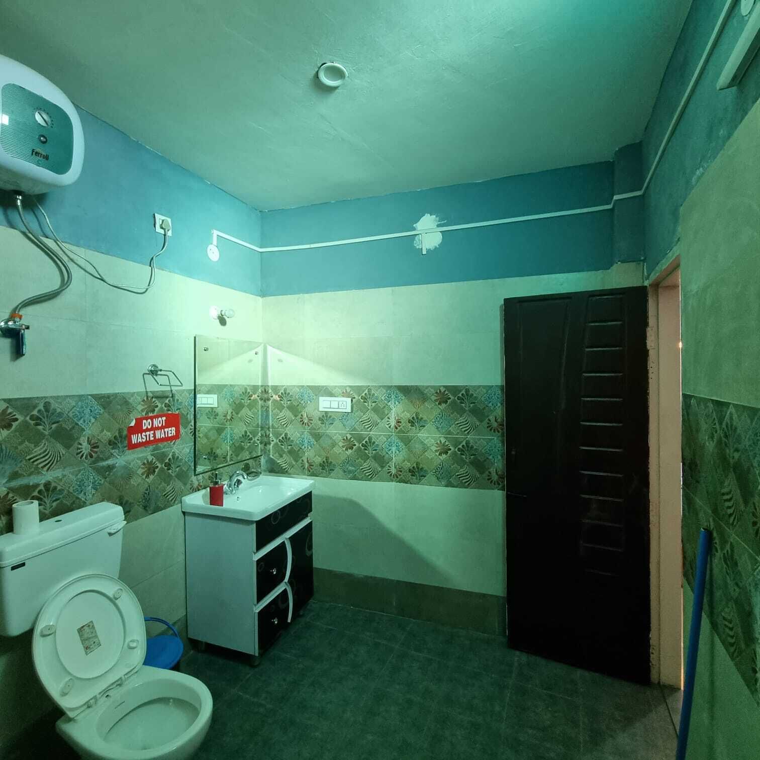 Une petite salle de bain avec des toilettes, un lavabo et un miroir. Un panneau indiquant « Veuillez économiser l’eau » est affiché sur le mur.