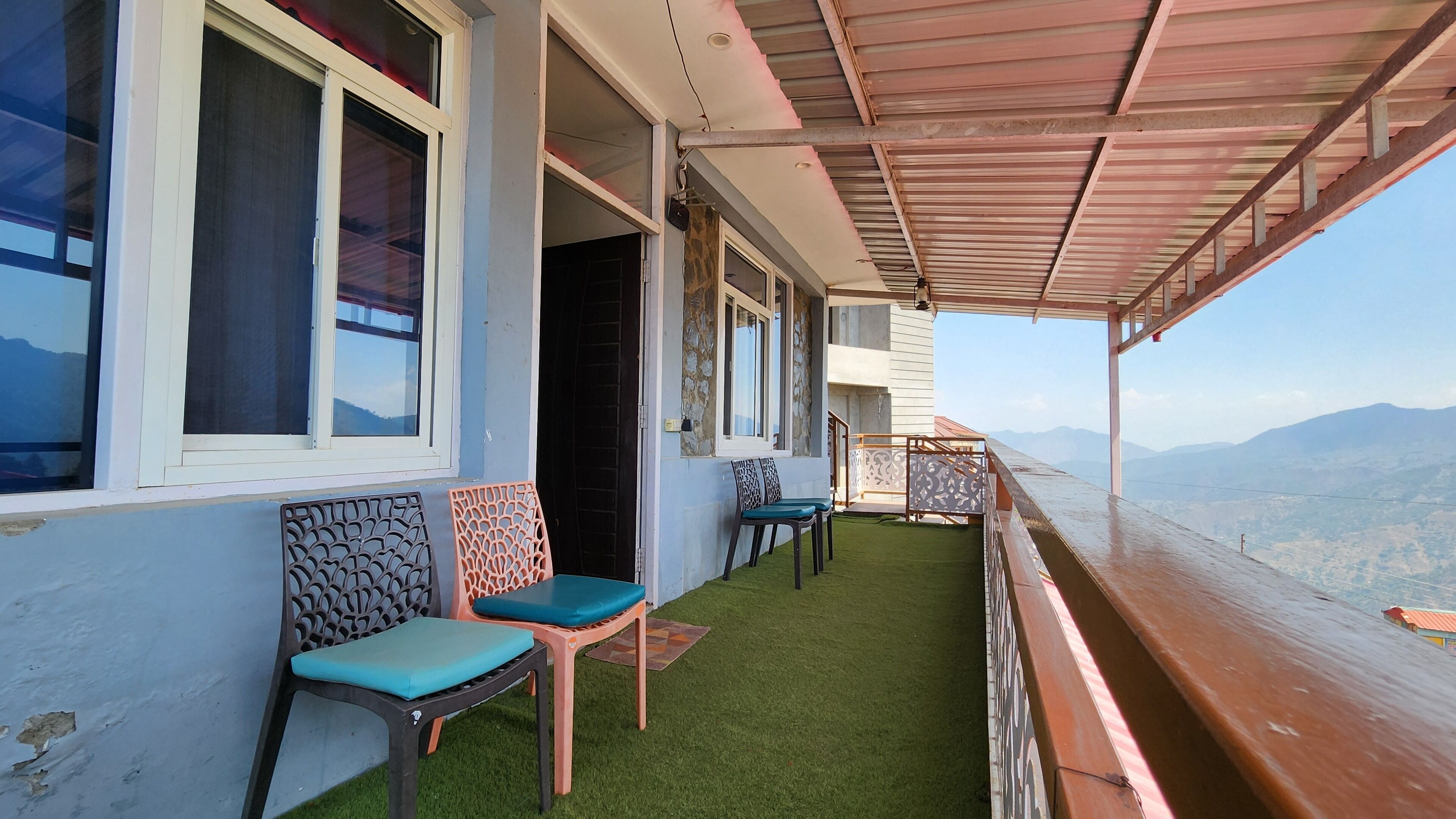 A balcony with two chairs, a wooden railing, and a view of mountains.