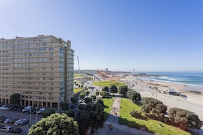 Un hotel de gran altura con varios pisos, estacionamiento y vista al mar.