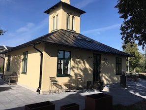 A building with a gabled roof, a chimney, and a small porch with chairs and tables. - Brohuspark (Lomma)