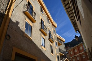 A multi-story building with balconies and large windows, featuring a stone facade and yellow trim. - Tres Puentes Anguiano (Anguiano)