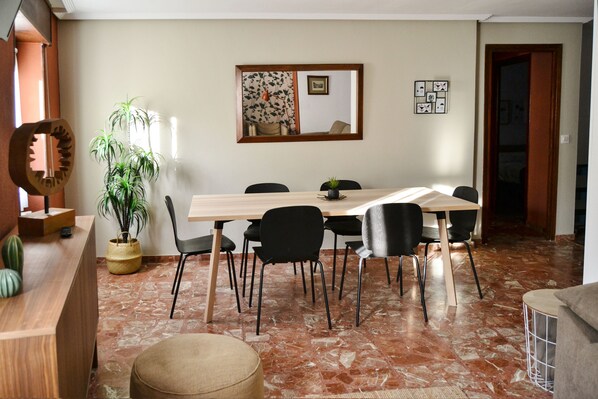 A dining area with a wooden table, black chairs, a potted plant, and a mirror on the wall. - Tres Puentes Anguiano (Anguiano)