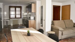 A modern kitchen with a dining area, a sofa, and a small table. - Tres Puentes Anguiano (Anguiano)