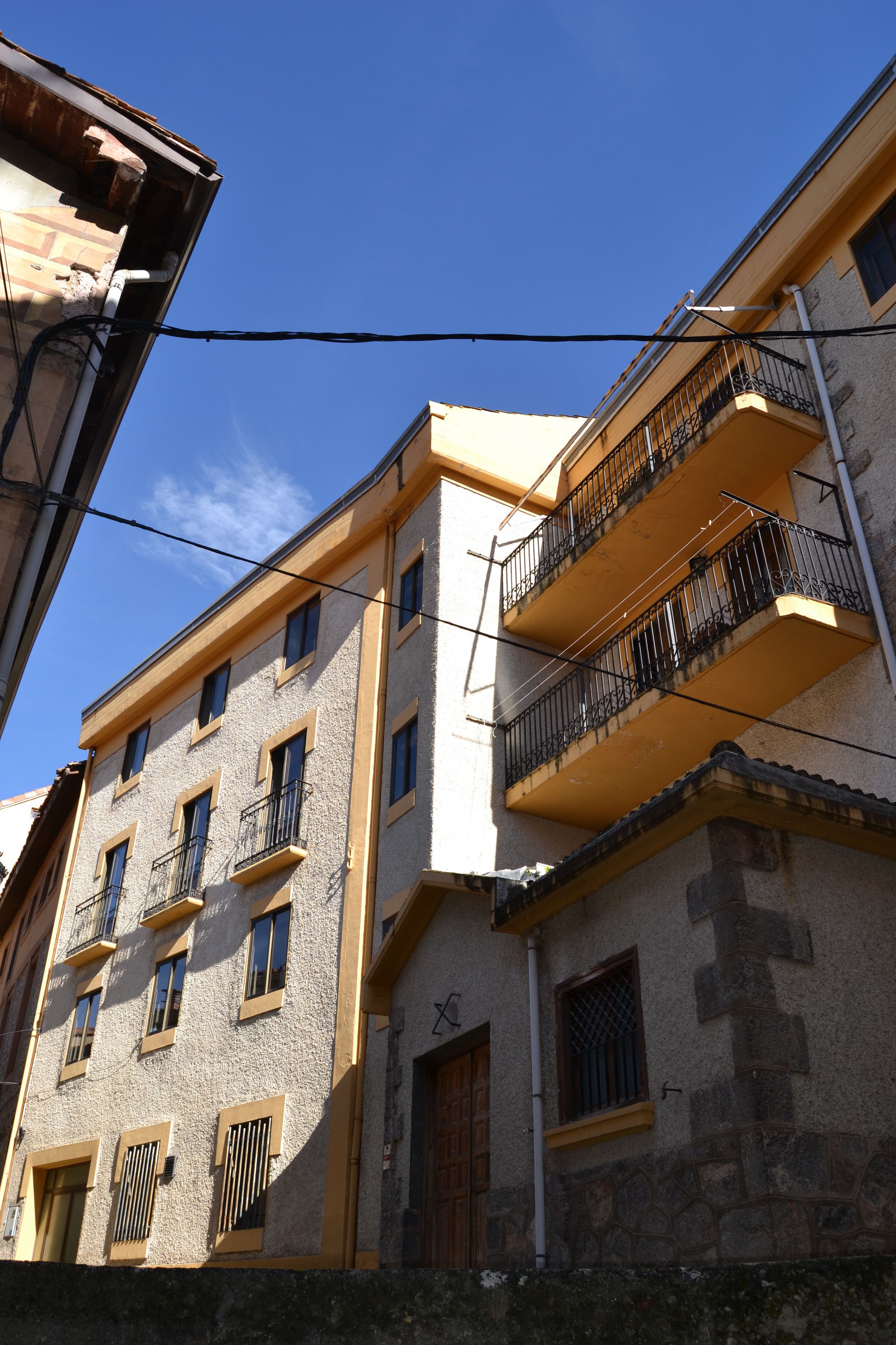 A multi-story building with balconies, a stone facade, and a clear blue sky.
