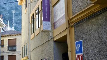 Un edificio con fachada amarilla, una escalera visible y una señal de estacionamiento.