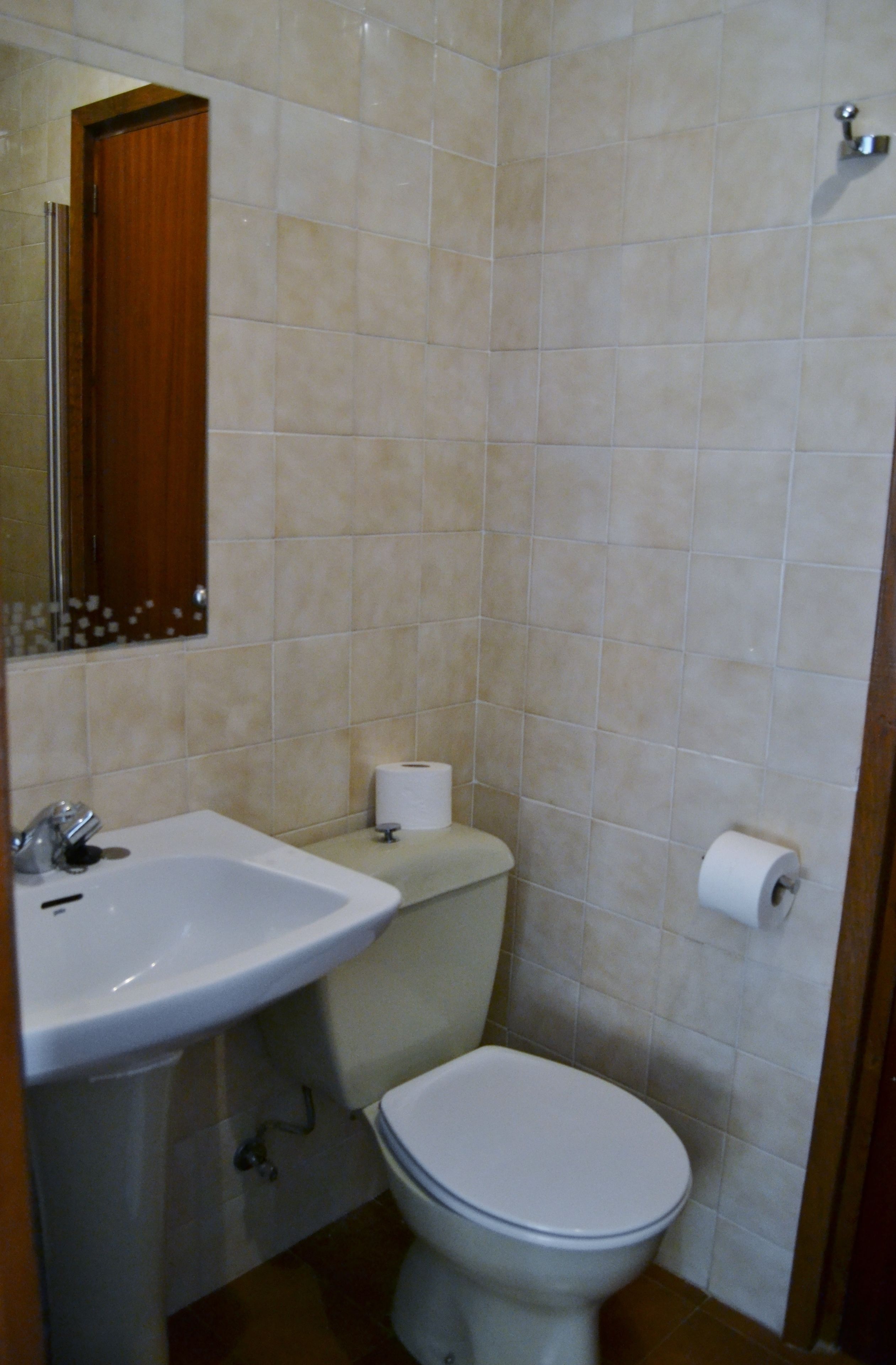 Een badkamer met een wastafel, toilet en spiegel.