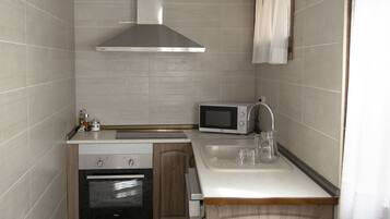A compact kitchen with a microwave, oven, and sink.