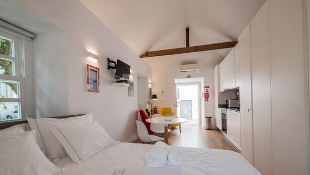 A hotel room with a large bed, a small dining area, and a kitchenette. - Soul House - Exclusive Apartment - Your Home away from Home (Lisboa)