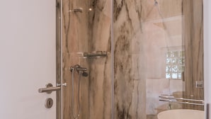 A modern bathroom with a glass-enclosed shower, a white sink, and marble walls. - Soul House - Exclusive Apartment - Your Home away from Home (Lisboa)