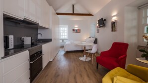 A compact kitchen with modern appliances, a dining area with a round table and chairs, a red armchair, and a yellow sofa. - Soul House - Exclusive Apartment - Your Home away from Home (Lisboa)
