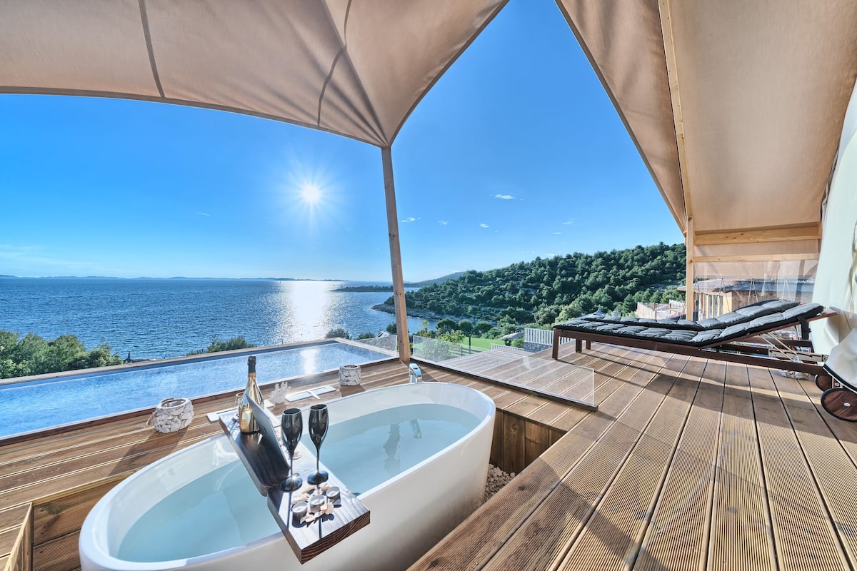 A luxurious outdoor hot tub with a view of a lake and hills.