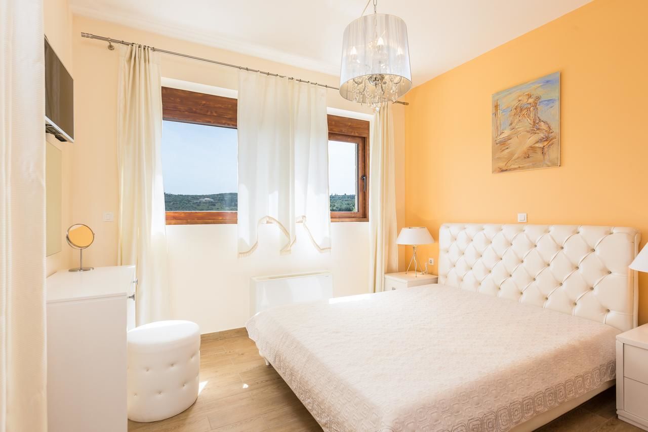 Een slaapkamer met een groot bed, een raam met gordijnen, een nachtkastje met een lamp en een schilderij aan de muur.