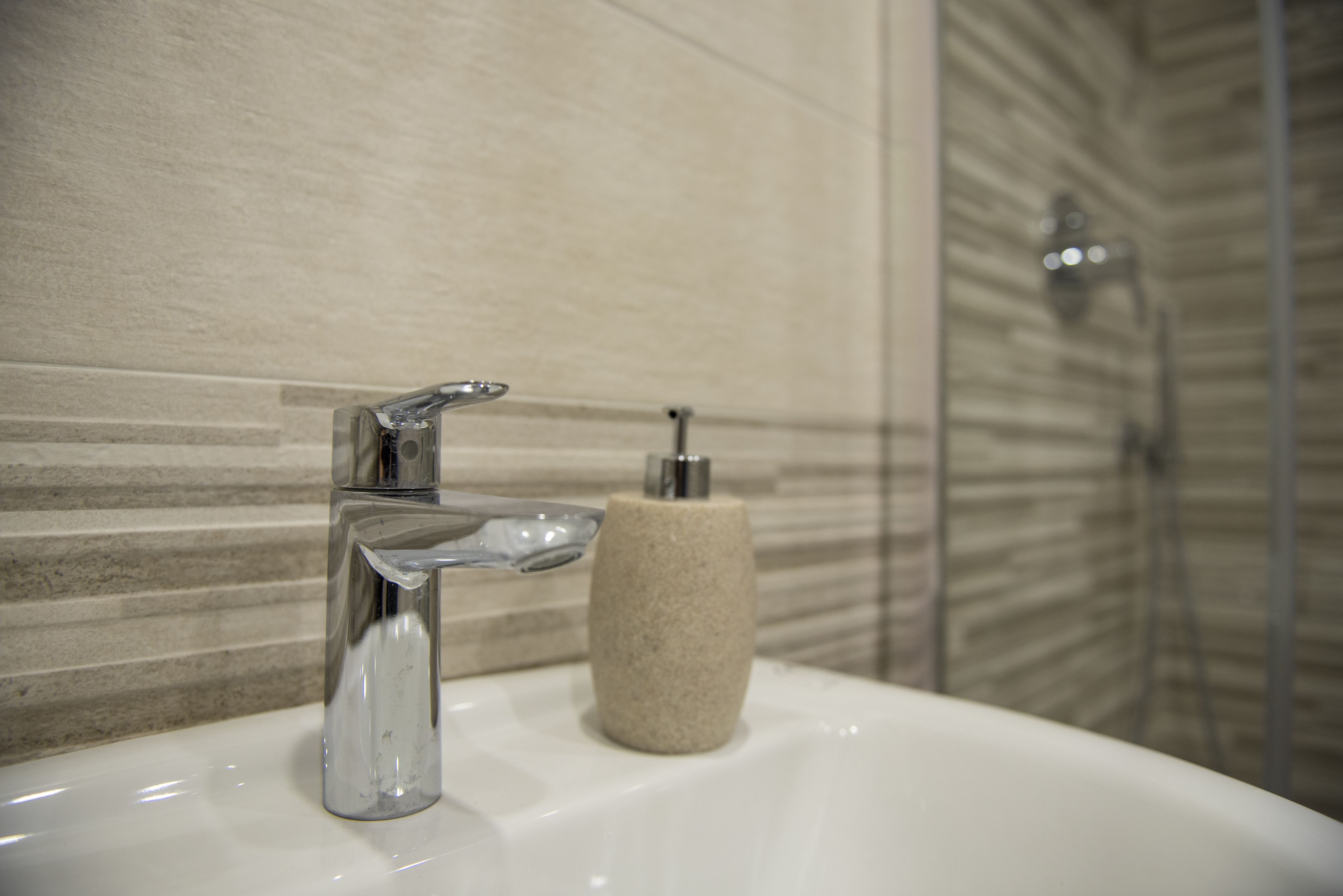 A bathroom sink with a chrome faucet and a soap dispenser.