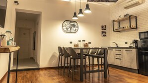 Een moderne keuken met een eethoek, met een houten vloer, een witte baksteenmuur en hangende lampen.