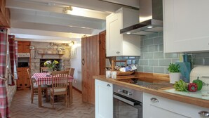 A compact kitchen with white cabinets, a wooden countertop, and a herringbone-patterned floor. - 3 bedroom accommodation in Nanpean, near St Austell (Nanpean, near St Austell)