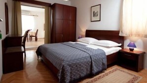 A bedroom with a bed, wooden wardrobe, bedside table, and a lamp. - Apartments Begic (Makarska)