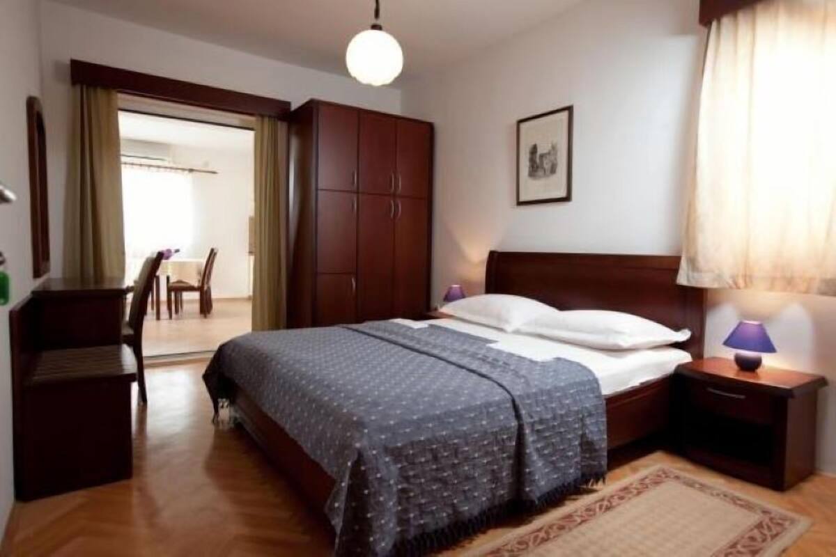 Une chambre à coucher avec un lit, une armoire en bois, une table de chevet et une lampe.
