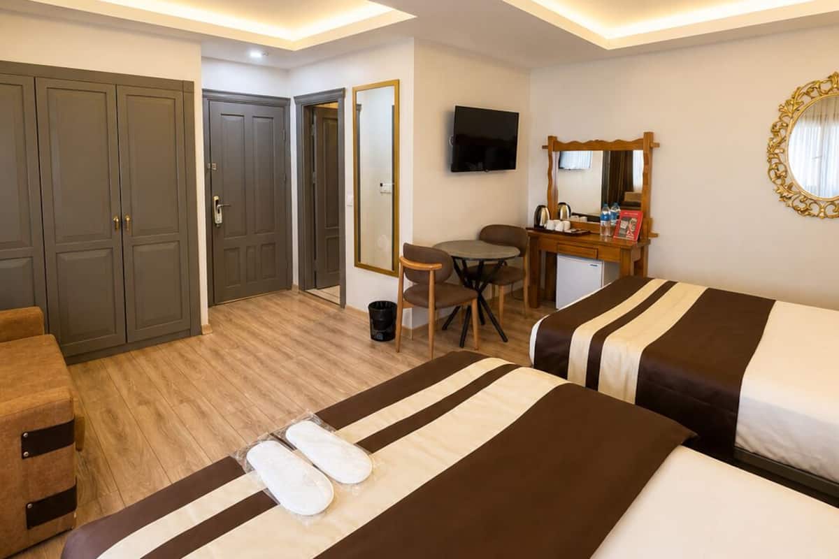 A hotel room with two beds, a desk, a TV, a mirror, and a wardrobe.