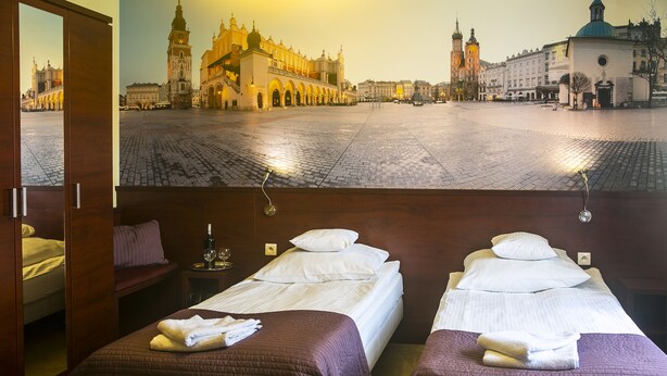 Habitación de hotel con dos camas, vista a un mural urbano y una puerta de madera.