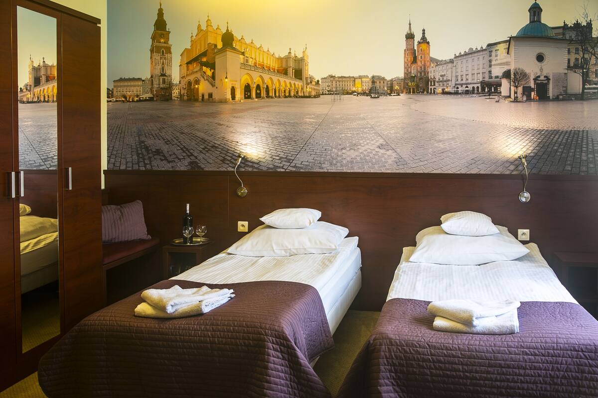 Habitación de hotel con dos camas, vista a un mural urbano y una puerta de madera.