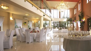 Un amplio salón de banquetes bien iluminado, con techos altos, candelabros y suelo pulido.