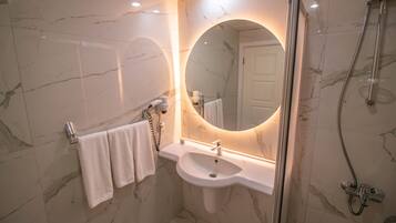 A bathroom with a marble sink, a large mirror, and a shower.