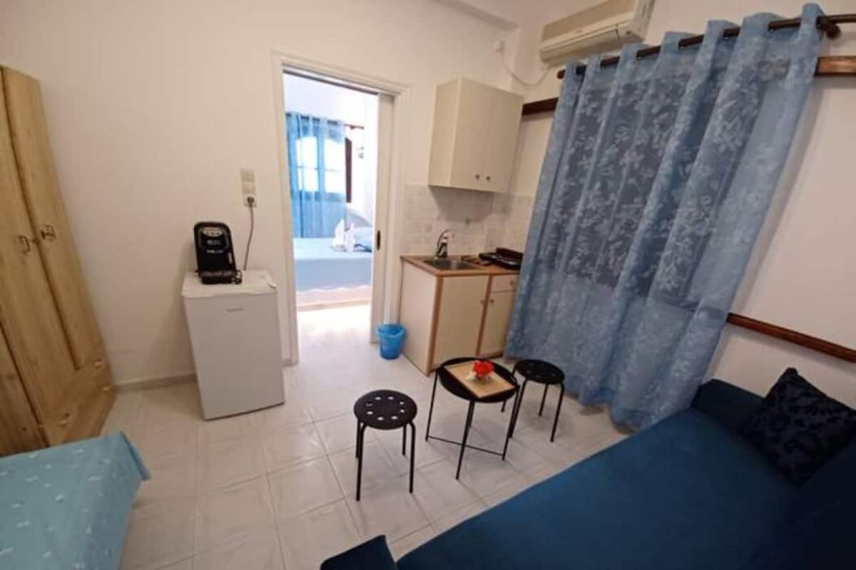 Un espai habitable compacte amb una cuineta, zona de dinar i zona d'estar amb sofà i cadires.