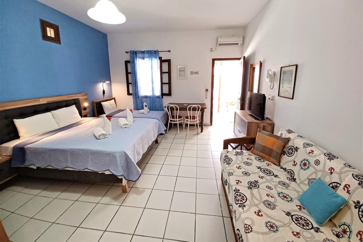 Habitació d'hotel amb dos llits, un sofà, una televisió, un escriptori i una cadira.