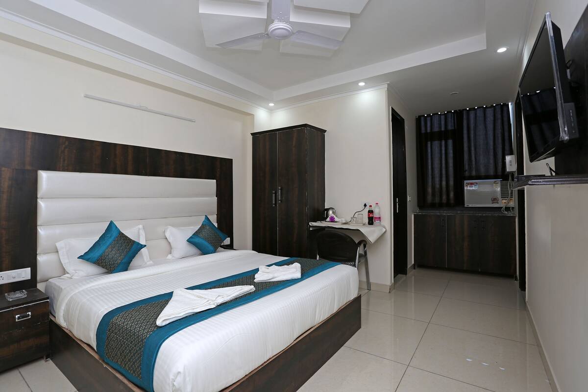 A modern hotel room with a large bed, a desk, and a television.