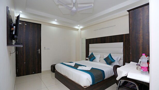 A hotel room with a bed, a desk, a chair, a TV, and a wardrobe. - Hotel Capital Mount (New Delhi)