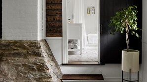 A doorway leading to a room with a white door, a stone wall, a wooden door frame, and a potted plant. - 1805 Farmhouse with Heated Pool in Harpers Ferry (Harpers Ferry)