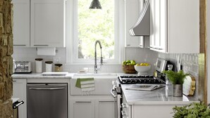 A modern kitchen with white cabinets, a stainless steel dishwasher, a gas stove, and a window with a view of greenery. - 1805 Farmhouse with Heated Pool in Harpers Ferry (Harpers Ferry)