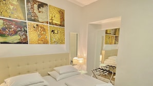Habitación de hotel con una cama grande, una mesita de noche con lámpara y vistas a un baño con perchero para toallas.