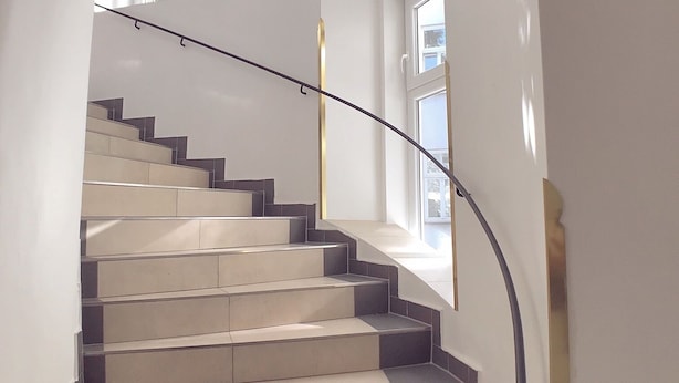 Una escalera moderna con barandilla de vidrio que conduce a una plataforma con ventana.