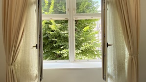 Una ventana con vista a un árbol y un edificio.