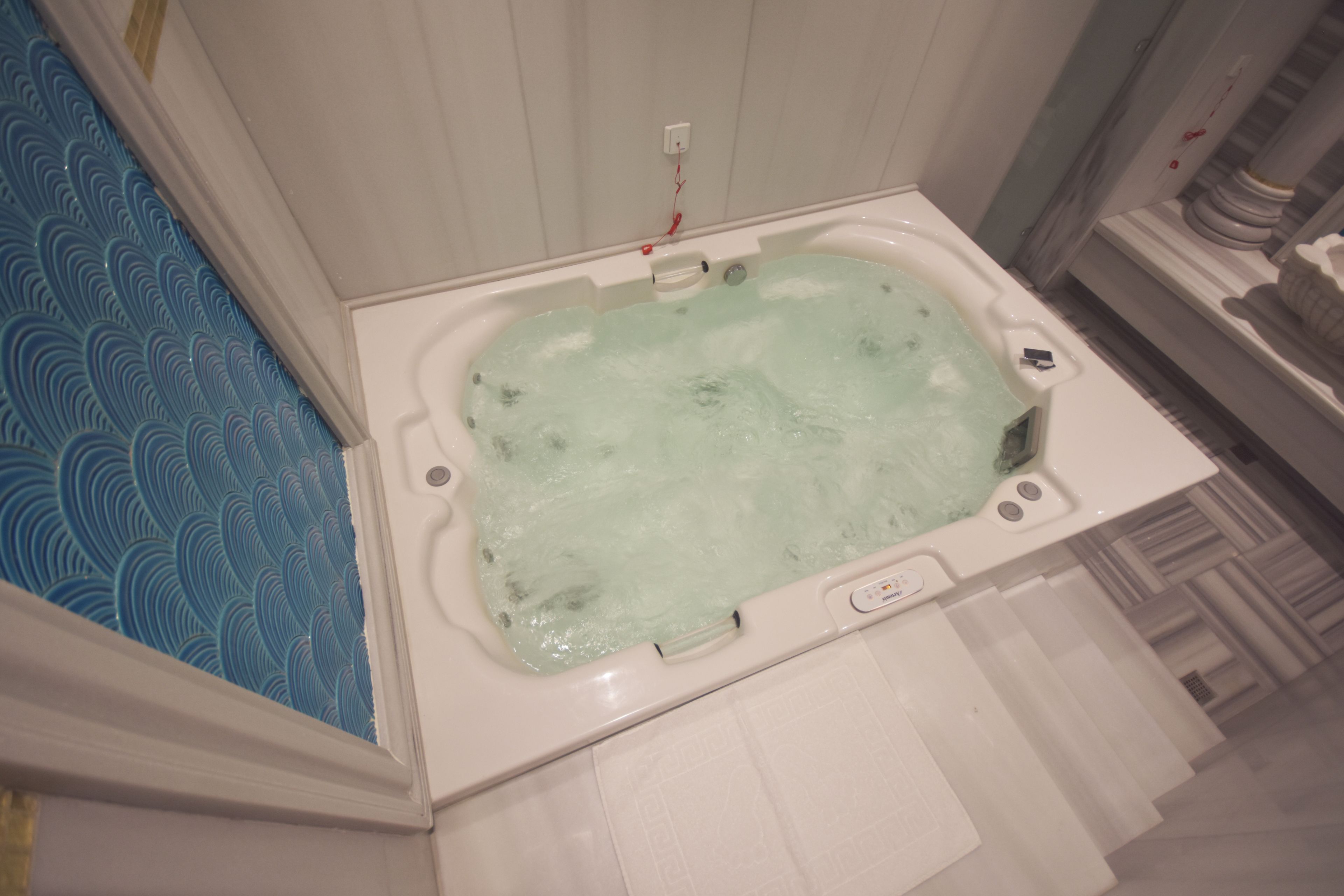 Un baño con bañera, un lavamanos blanco y una zona de ducha con diseño azulado.