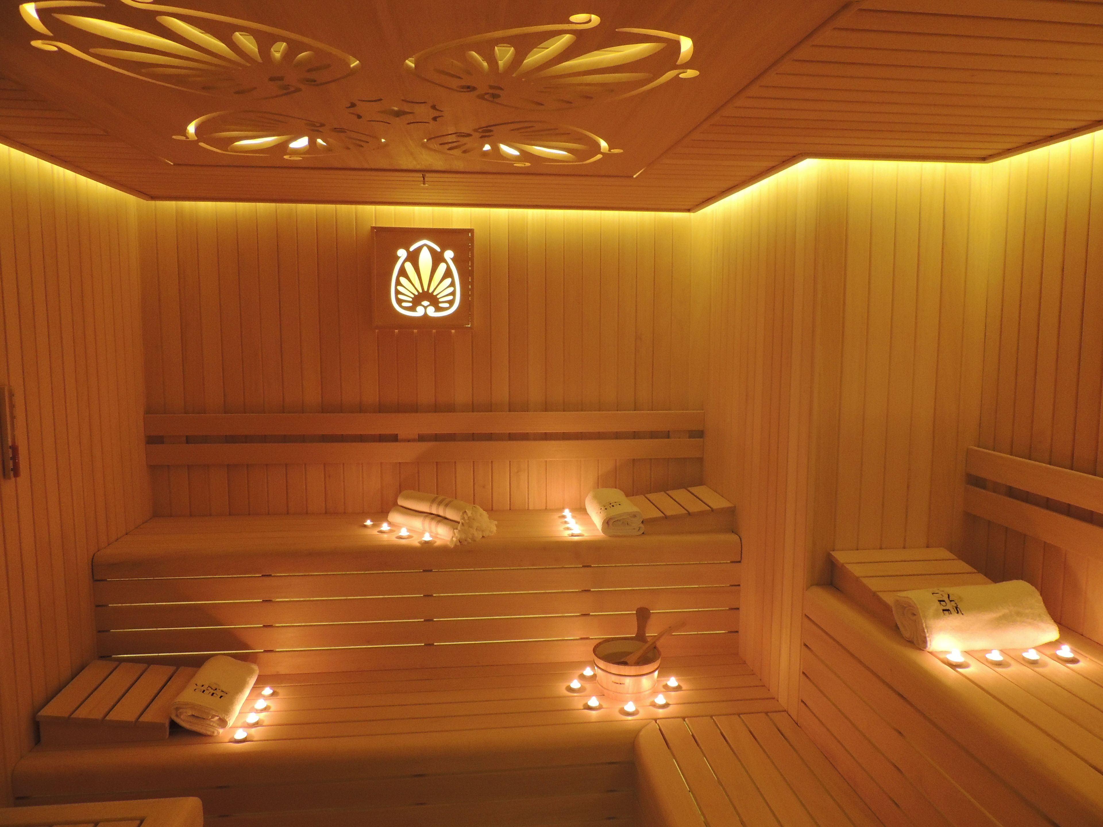 A wooden sauna with benches, candles, and a wooden bucket.