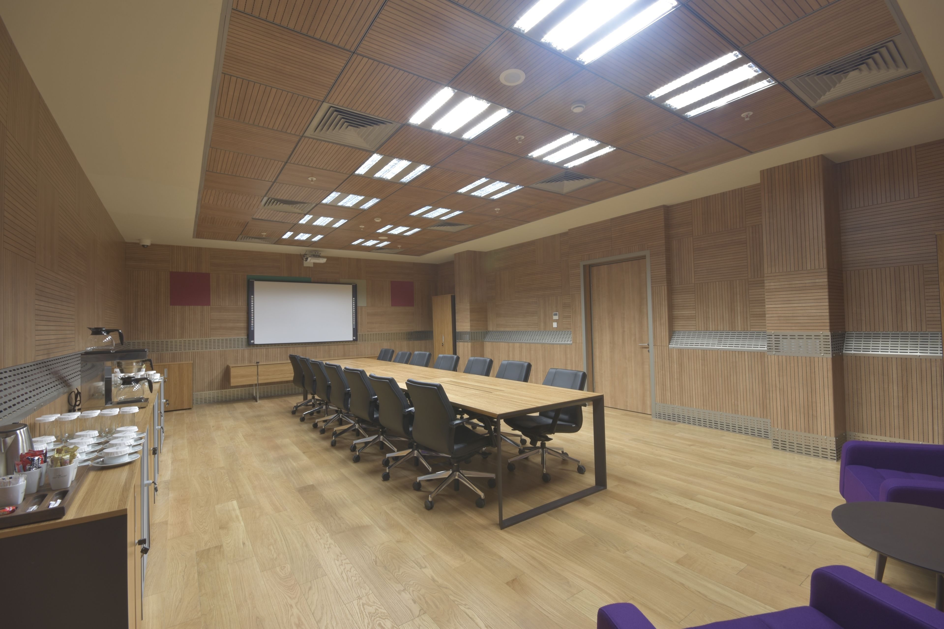 Una sala de conferències amb una taula llarga, cadires, una pantalla de projector i una pantalla de presentació.